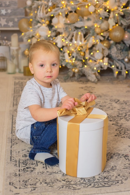 bambino felice a Natale con regalo ragazzo vicino all'albero di Natale