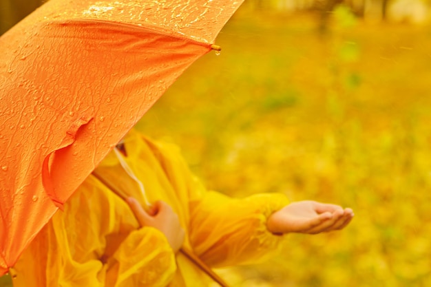 Bambino felice che cattura le gocce di pioggia nel parco autunnale