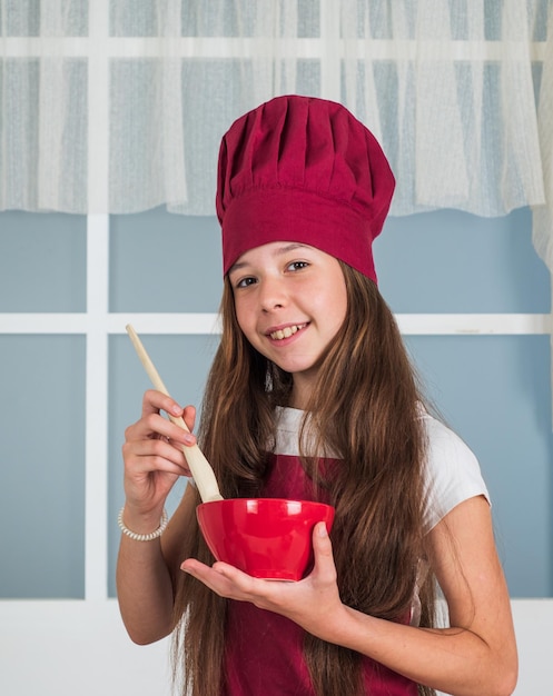 Bambino felice che cucina in cucina uniforme