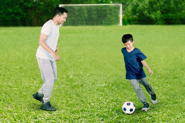 Bambino felice che fa esercizi di calcio con suo padre