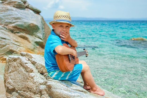 Bambino felice che gioca chitarra in riva al mare