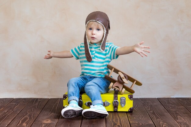 Bambino felice che gioca con l'aeroplano di legno dell'annata