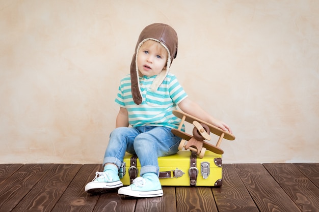 Bambino felice che gioca con l'aeroplano di legno dell'annata