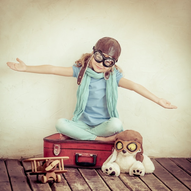 Bambino felice che gioca con l'aeroplano giocattolo a casa. dai toni retrò