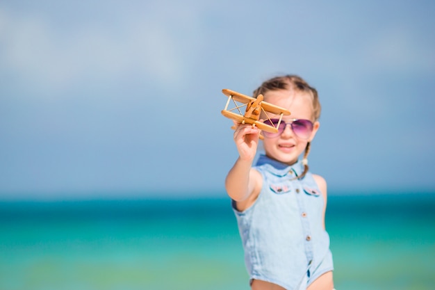 Bambino felice che gioca con l'aeroplano giocattolo sulla spiaggia.