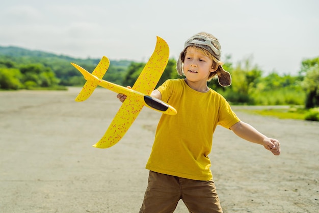 Bambino felice che gioca con l'aeroplano giocattolo sullo sfondo della vecchia pista Viaggiare con il concetto di bambini