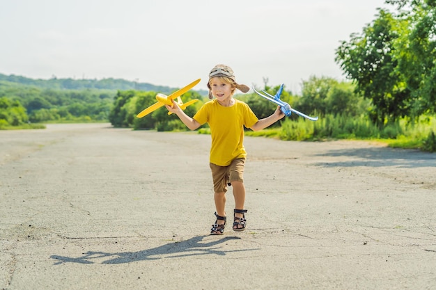 Bambino felice che gioca con l'aeroplano giocattolo sullo sfondo della vecchia pista Viaggiare con il concetto di bambini