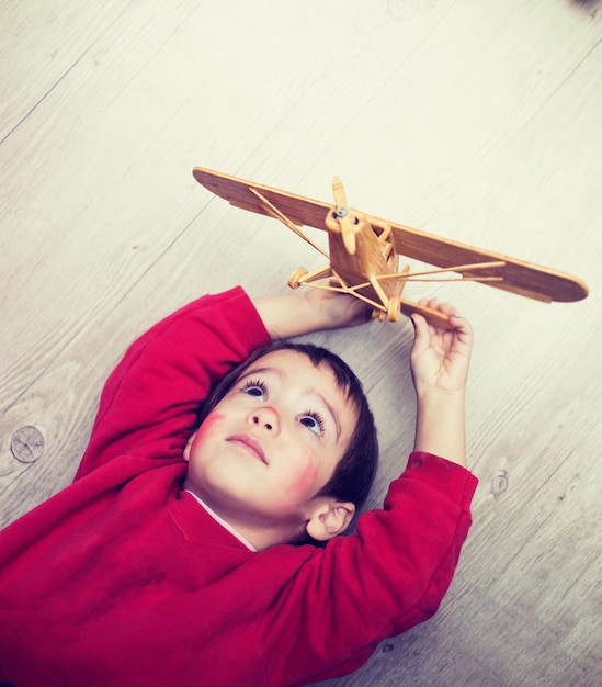 Bambino felice che gioca con l&#39;aeroplano giocattolo