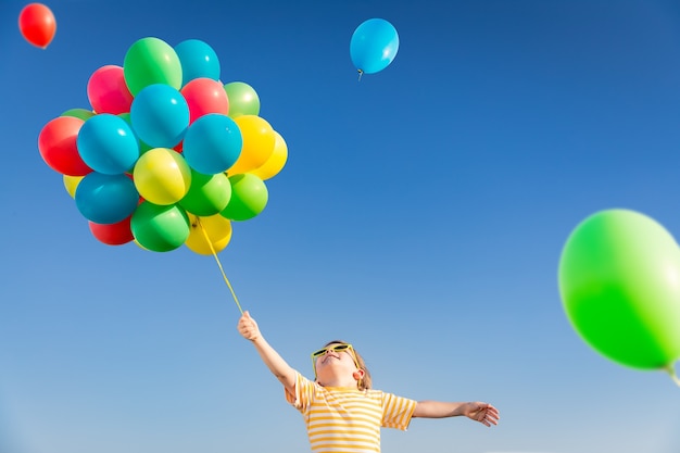 Bambino felice che gioca con palloncini multicolori luminosi all'aperto