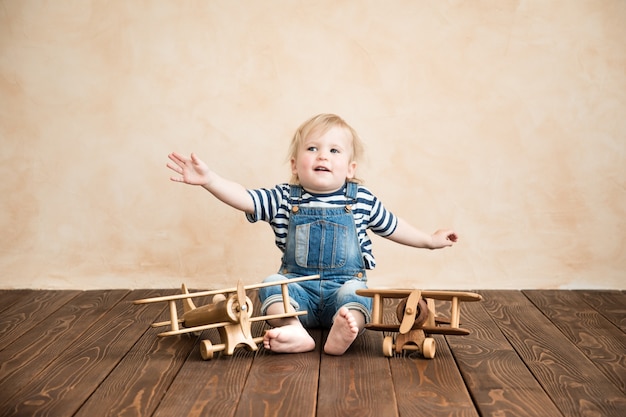 Bambino felice che gioca in casa. Bambino con aeroplanino giocattolo