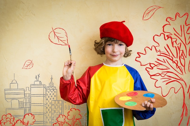 Bambino felice che gioca in casa. Tema autunnale di disegno. Immaginazione e concetto di libertà