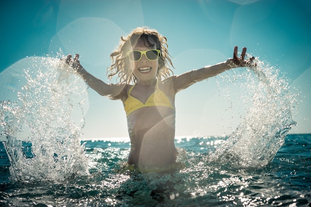 bambino felice che gioca nel mare