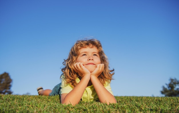 Bambino felice che gioca sull'erba verde bambino divertente all'aperto nel concetto di giorno dei bambini del giardino di primavera