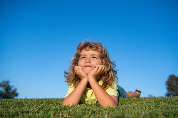 Bambino felice che gioca sull'erba verde bambino divertente all'aperto nel concetto di giorno dei bambini del giardino di primavera