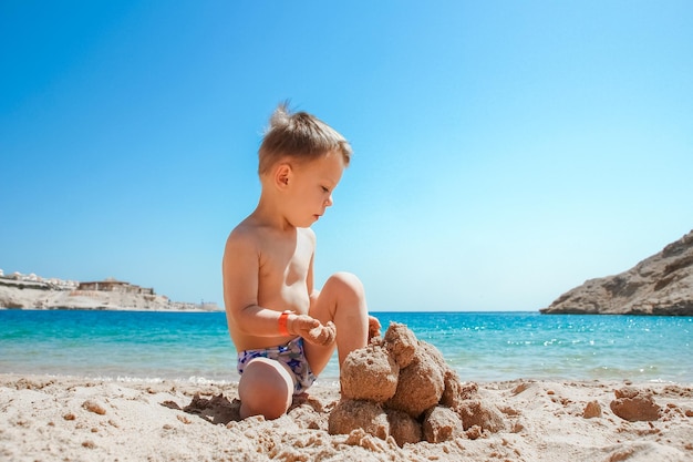 Bambino felice che gioca sullo sfondo del mare