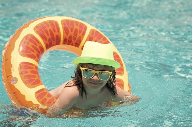 Bambino felice che gode delle vacanze estive all'aperto nell'acqua in piscina