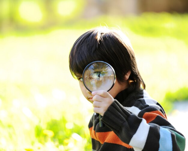 Bambino felice che gode soleggiata tarda estate e giorno di autunno in natura su erba verde