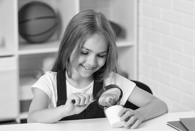 Bambino felice che guarda la pianta attraverso la scoperta della lente d'ingrandimento