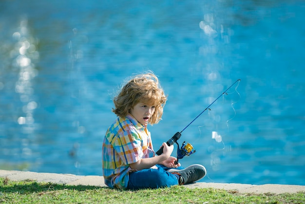 Bambino felice che pesca sul lago ragazzo con spinner al concetto di pesca fluviale