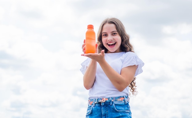 Bambino felice che presenta succo o acqua in bottiglia per rinfrescare la vitamina