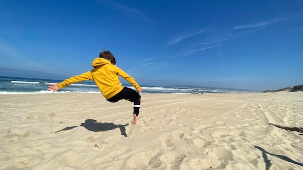 Bambino felice che salta sopra la sabbia su una spiaggia Giorno soleggiato. Portogallo