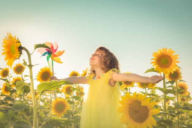 Bambino felice che si diverte in campo primaverile su sfondo azzurro del cielo Concetto di libertà