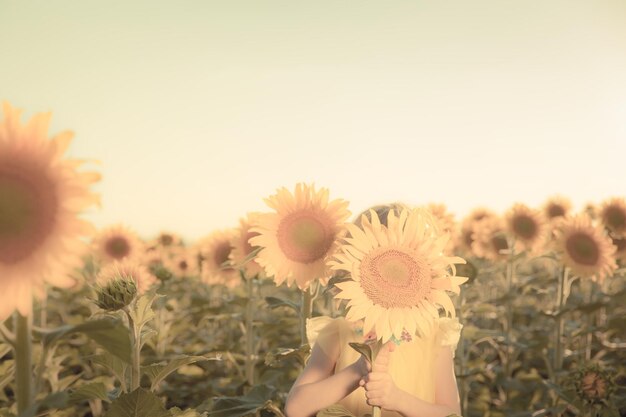 Bambino felice che si diverte in campo primaverile su sfondo azzurro del cielo Concetto di libertà