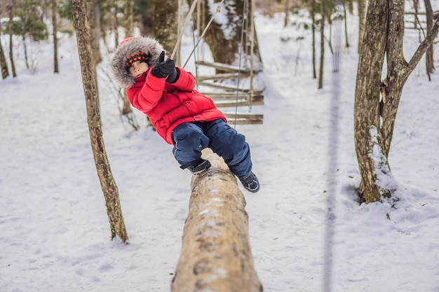 Bambino felice che si gode l'attività in un parco avventura di arrampicata in una giornata invernale