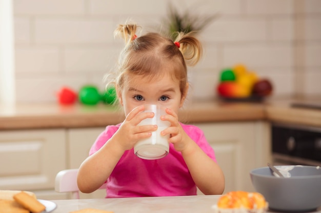 Bambino felice che si siede al tavolo in cucina e mangia con appetito