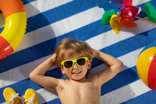 Bambino felice che si trova sul tovagliolo a strisce all'aperto