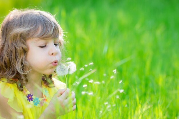 bambino felice che soffia fiore di tarassaco all'aperto ragazza che si diverte nel parco di primavera spring