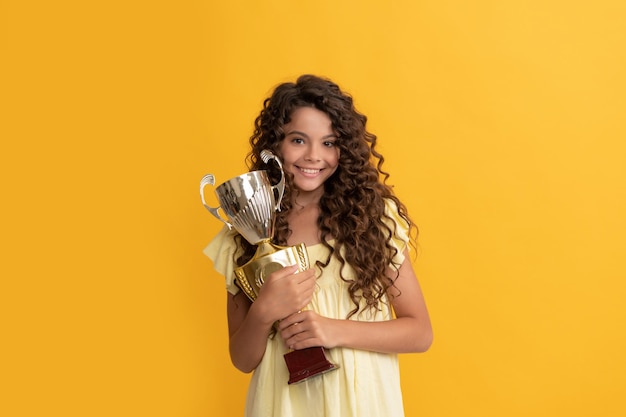 Bambino felice che tiene la coppa del campione d'oro come vincitore, premio.