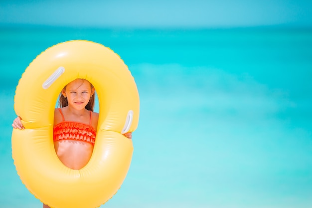 Bambino felice con cerchio di gomma gonfiabile divertendosi sulla spiaggia