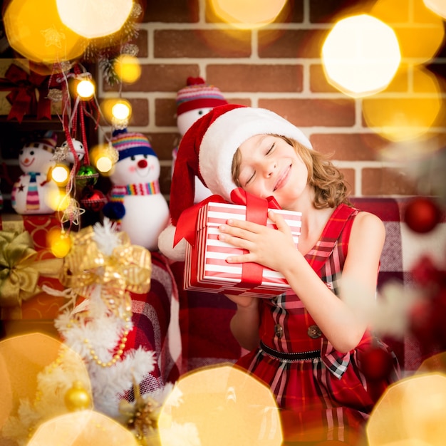 Bambino felice con confezione regalo di Natale. Bambino divertente che gioca a casa