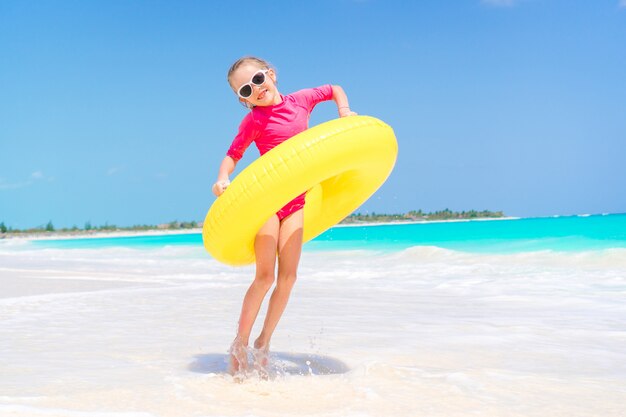 Bambino felice con il cerchio di gomma gonfiabile divertendosi sulla spiaggia bianca