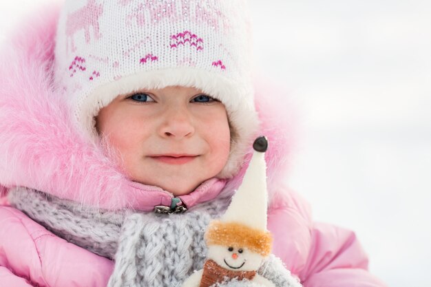 Bambino felice con il pupazzo di neve nel parco invernale