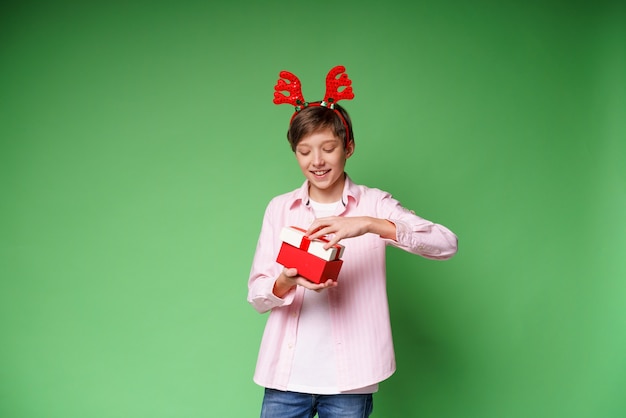 Bambino felice con il regalo di capodanno su sfondo verde studio copia spazio ragazzo eccitato con un accesso di cervo...