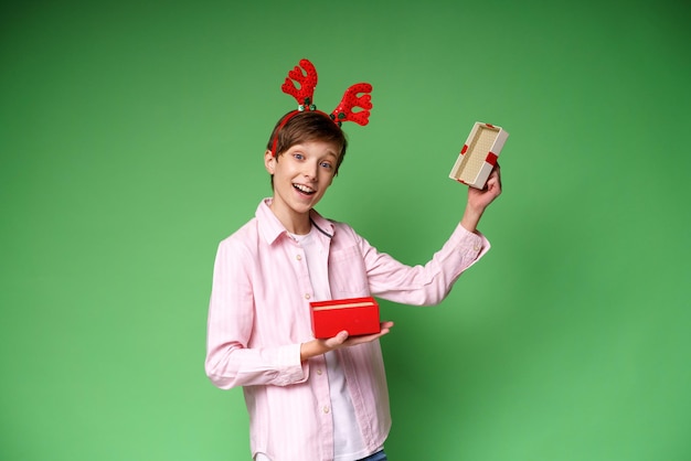 Bambino felice con il regalo di capodanno su sfondo verde studio copia spazio ragazzo eccitato con un accesso di cervo...