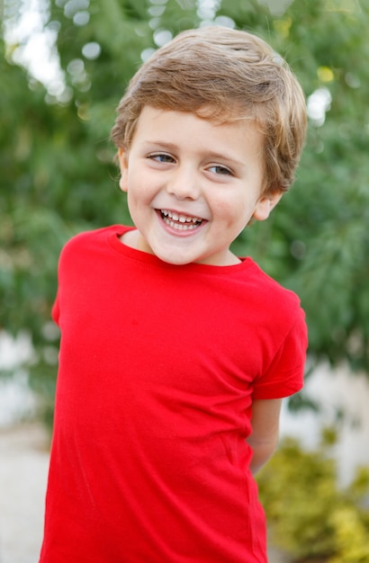 Bambino felice con la maglietta rossa nel giardino