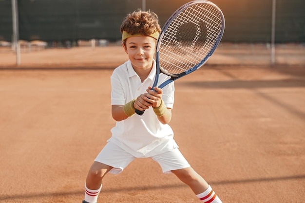 Bambino felice con la racchetta da tennis in campo