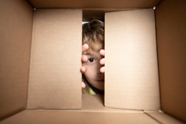 Bambino felice con la scatola di cartone che disimballa il pacco dal negozio di Internet per bambini soddisfatto del veloce