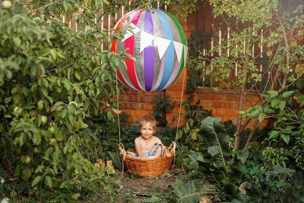 Bambino felice con mongolfiera al tramonto in mongolfiera estiva