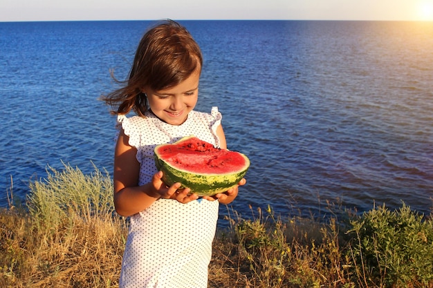 Bambino felice con un cocomero in mano sulla spiaggia Ragazza con un cocomero