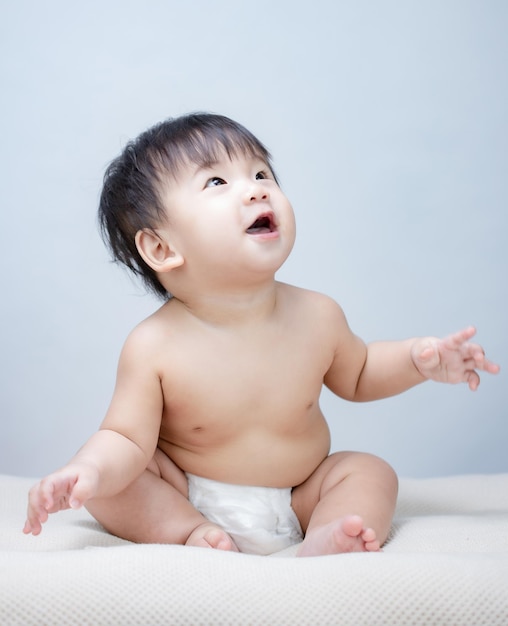 Bambino felice del bambino che si siede nel pannolino sul letto