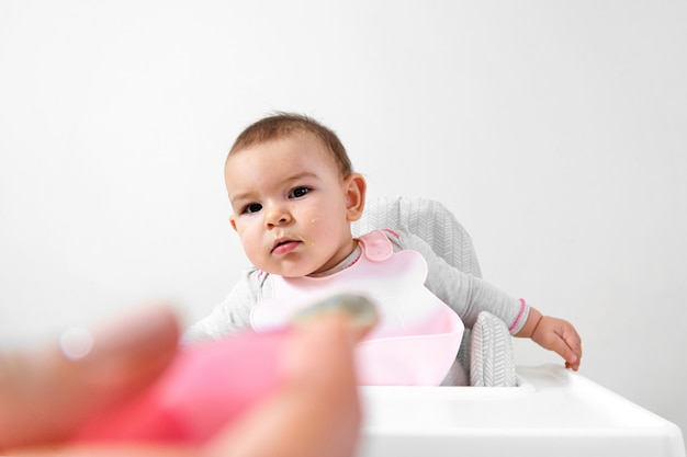 Bambino felice del bambino nel seggiolone con il cucchiaio in mano