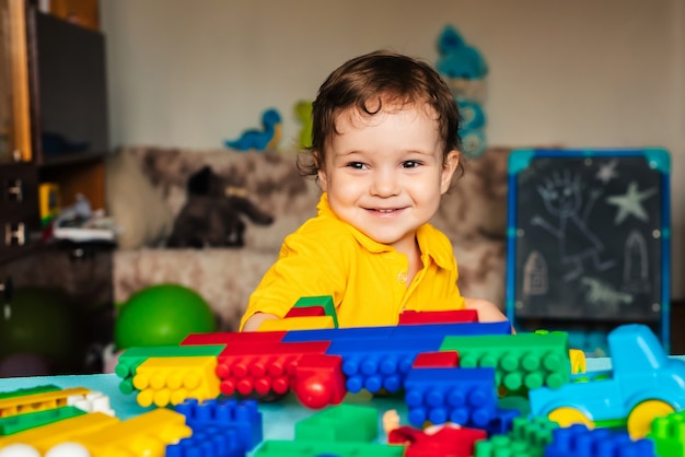 Bambino felice del ragazzo che gioca a casa con i blocchi colorati