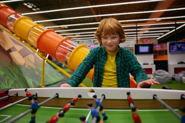 Bambino felice e eccitato che gioca a calcio da tavolo al centro di intrattenimento