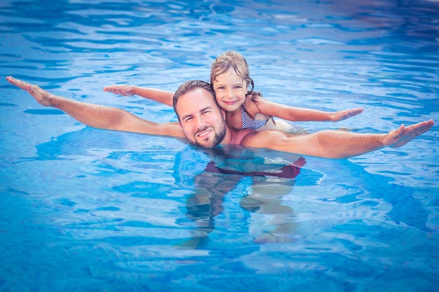 Bambino felice e padre che giocano in piscina