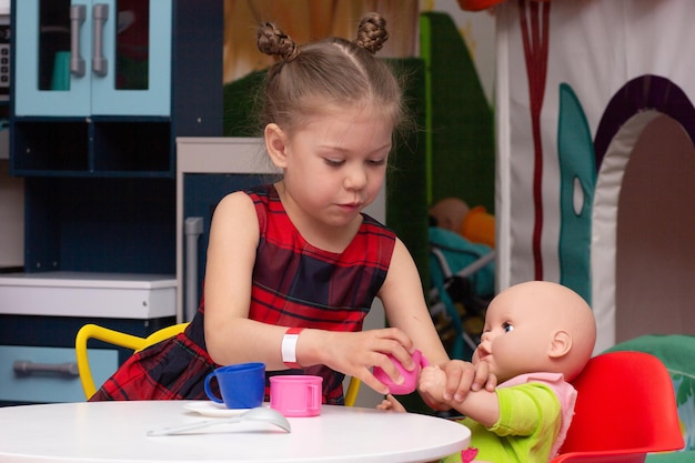 Bambino felice e sorridente che alimenta la bambola del tè