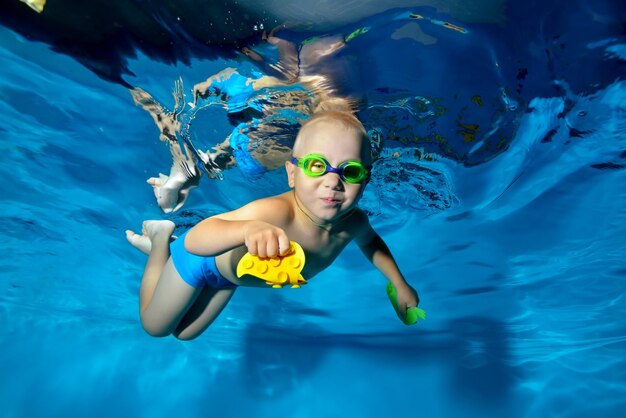 Bambino felice impegnato in sport che nuotano in piscina